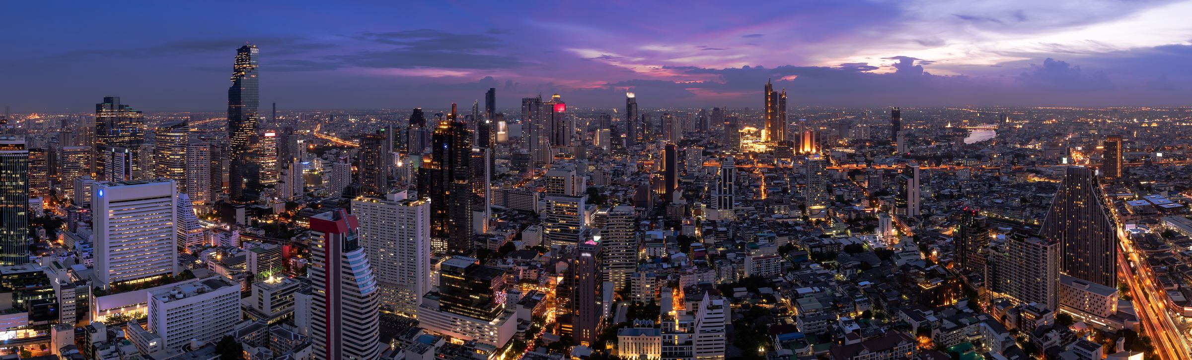 The Bangkok business district skyline at twilight, with the Chao Phraya river in the distance